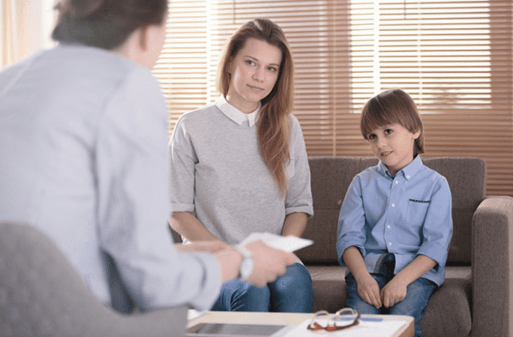a mother and her child consult with a male professional