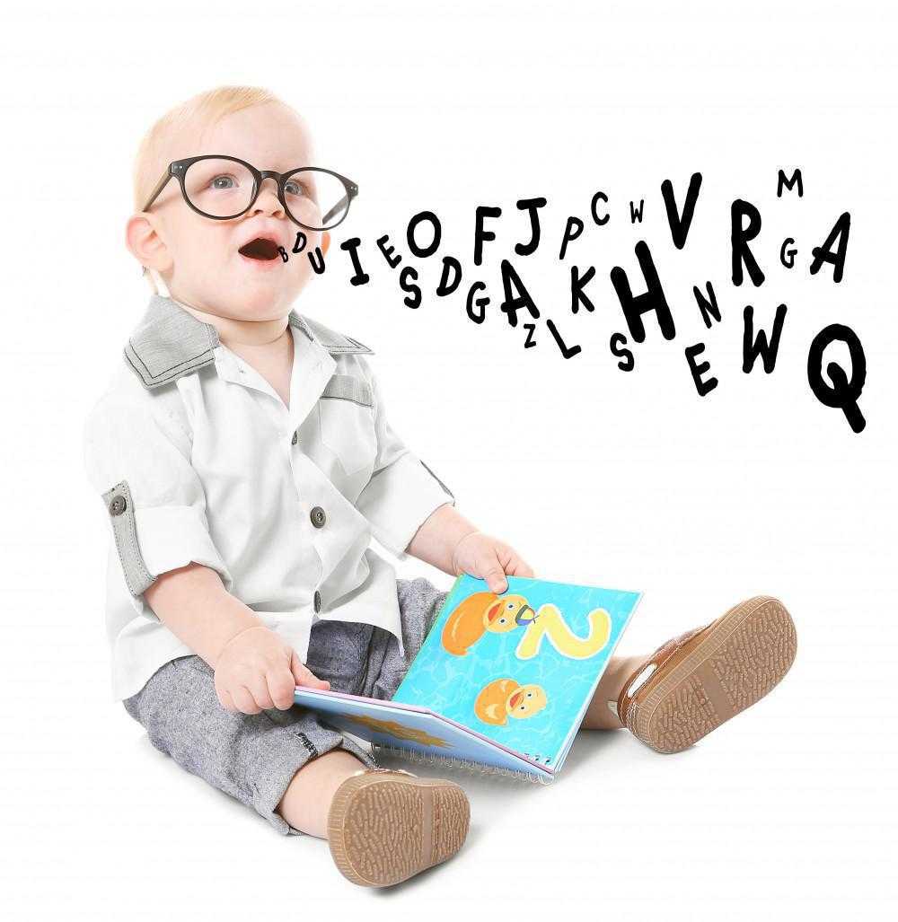 baby with glasses reading a book and letters are coming out of his mouth, representative of speech therapy and learning the alphabet