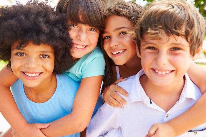 four children smile at the camera and embrace for the camera