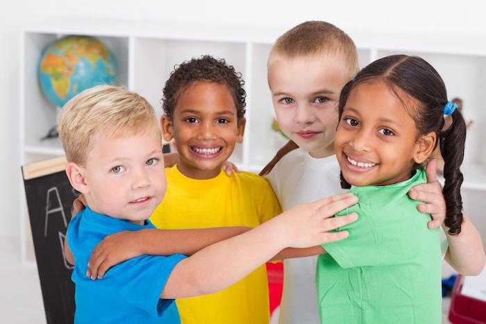 four children smile for the camera and hug