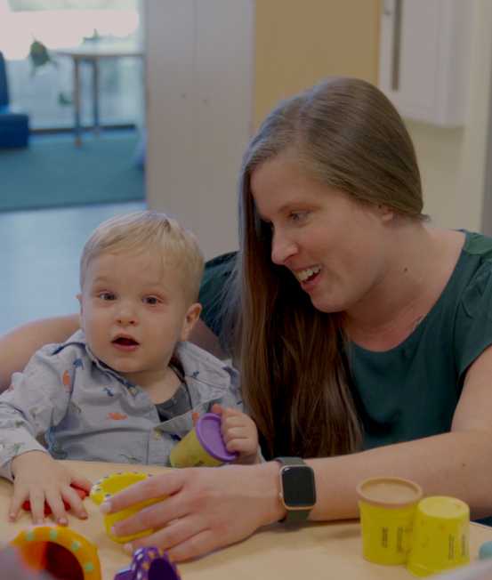 a teacher plays with toys with a child sitting at a table