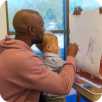 an icon of a child and a teacher drawing at an easel