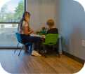 an icon of a child and a teacher sitting at a desk in the corner of the room