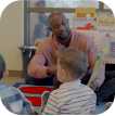 an icon of a male teacher reading to a group of children sitting on the floor