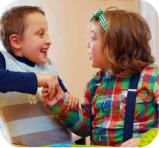 two children shake hands and smile at each other