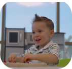 a child sits at a table and smiles