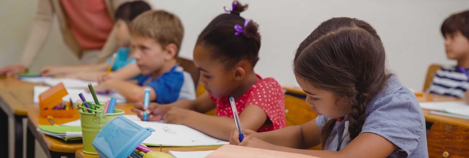 a group of children writing at a desk