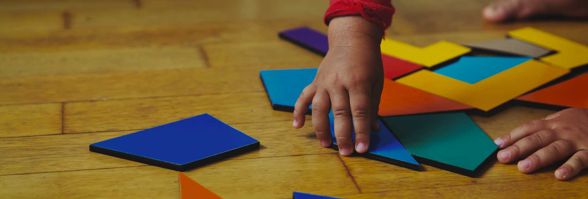 a child's hand reached for building toys on the floor