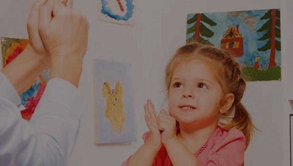 a young girl hand signs to a person off camera